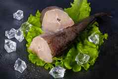 新鲜的冻鳕鱼尸体鱼角烹饪成分草本植物胡椒柠檬黑色的背景