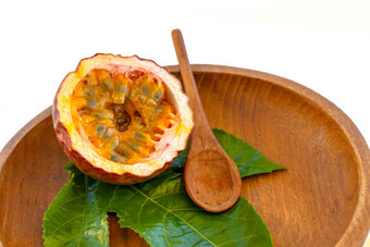 maracuja减少一半小玻璃容器皮水果木勺子叶板白色背景激情水果黄色的水果汁种子