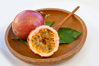 maracuja减少一半小玻璃容器皮水果木勺子叶板白色背景激情水果黄色的水果汁种子