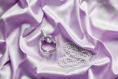 香水瓶珍珠淡紫色丝绸折叠织物背景