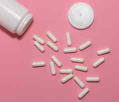 前视图分散处方白色药片容器帽粉红色的背景白色容器白色药片分散柔和的粉红色的背景医疗保健医疗制药概念
