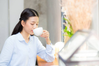 美丽的年轻的亚洲女人喝咖啡微笑