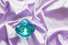 香水瓶淡紫色丝绸折叠织物背景
