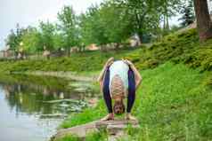 年轻的体育女孩实践瑜伽绿色草坪上河瑜伽阿三的姿势冥想团结自然