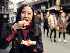 年轻的女人旅游享受吃日本街食物飞驒牛肉