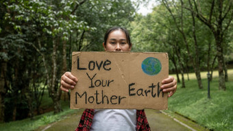女志愿者持有<strong>自然保护</strong>标志站<strong>自然</strong>森林概念世界环境一天