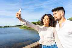 快乐夫妇爱使自拍假期海度假胜地日落年轻的美国黑人女人智能手机自画像的男朋友湖千禧一代生活自然