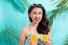 年轻的亚洲女人饮料汁玻璃色彩斑斓的蓝色的背景