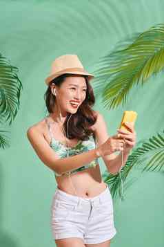 肖像幸福的亚洲女人穿夏天衣服听音乐蓝色的背景
