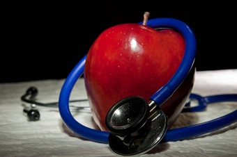 放大苹果包围蓝色的医疗听诊器