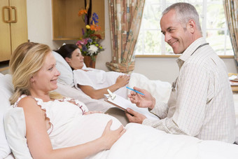 医生会说话的怀孕了女人持有图表微笑