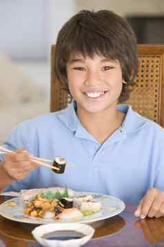 年轻的男孩餐厅房间吃中国人食物微笑