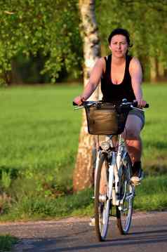 年轻的女人自行车游乐设施小巷桦木