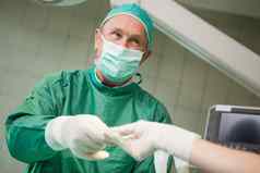 微笑外科医生采取工具戴着手套手