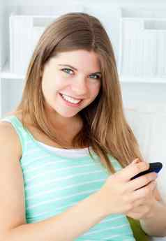 微笑年轻的女人发短信手机起居室