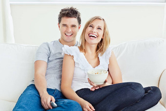 快乐的夫妇看电影爆玉米花坐着沙发