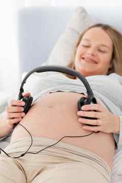 快乐怀孕了女人把耳机肚子