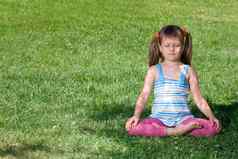 孩子坐冥想体式绿色草