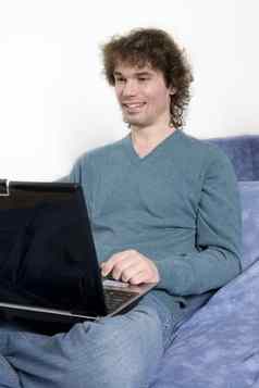年轻的中年男人。坐着沙发移动PC计算