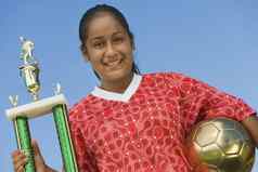 肖像年轻的女足球球员持有奖杯天空