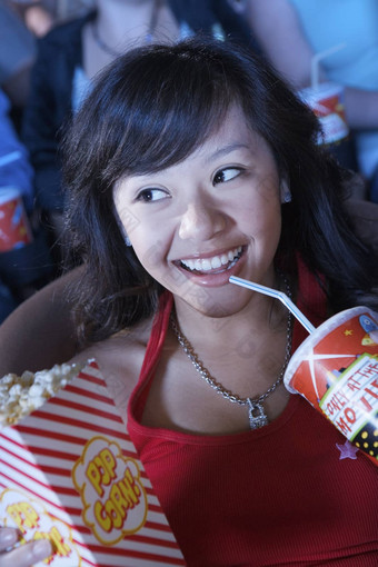 年轻的女看电影剧院采取sip喝