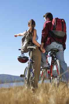 后视图年轻的夫妇站山自行车湖