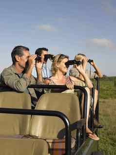 集团快乐游客坐着吉普车双筒望远镜