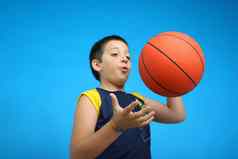 男孩玩篮球蓝色的背景