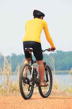 后视图年轻的自行车男人。穿骑手西装安全冥界