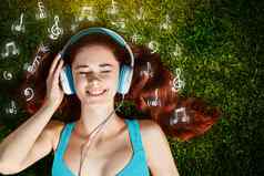 年轻的女人耳机绿色草公园音乐信息图表