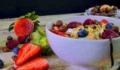 健康的早餐麦片酸奶草莓蓝莓树莓牛奶什锦早餐木乡村背景概念健身饮食健康早餐