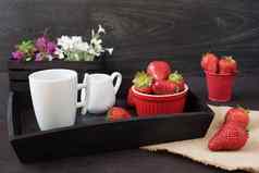 咖啡草莓木托盘黑色的表格白色紫色的花装饰木箱黑色的背景