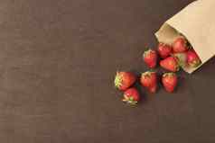 纸袋新鲜的红色的草莓新鲜的草莓小袋木风格表面小集团草莓黑暗木背景复制空间