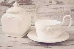 简单的乡村白色陶器空菜大杯咖啡前面天使瓷Jar成员木背景破旧的别致的古董着色