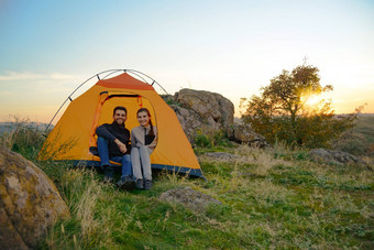 年轻的夫妇坐着帐篷美女晚上山冒险家庭旅行