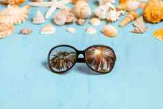 蓝色的海背景太阳镜贝壳夏天假期假期时间概念