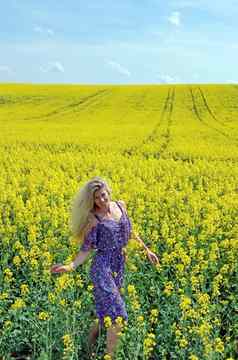 金发女郎女孩衣服花打印盛开的黄色的油菜籽场