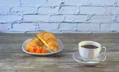 传统的早餐杯黑色的咖啡羊角面包片橙色表格特写镜头