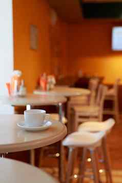 咖啡杯表格咖啡馆模糊的背景白色茶杯早餐咖啡馆背景橙色