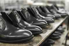 很多黑色的闪亮的鞋子架子上鞋工厂完成了货物仓库