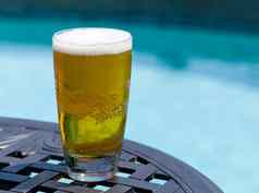 玻璃啤酒表格在游泳池边