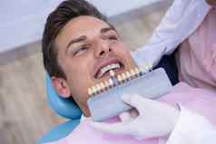 牙医持有设备检查男人。医疗诊所