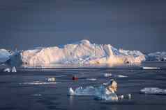 红色的帆船巡航浮动冰山迪斯科湾冰川午夜太阳季节极地夏天伊卢利萨特格陵兰岛