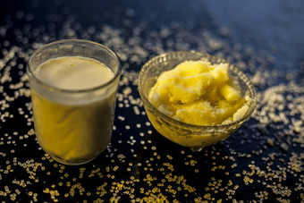 关闭玻璃碗纯牛奶混合热牛奶黑色的木光滑的表面生酥油澄清黄油糖晶体传播表面水平拍摄