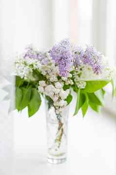 淡紫色花玻璃花瓶窗口窗台上自然春天背景白色紫罗兰色的花