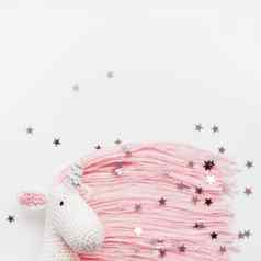 可爱的仙女独角兽粉红色的鬃毛尾巴使线程钩针编织的手使玩具白色背景银星星五彩纸屑时尚的生物象征魔法奇迹的地方文本