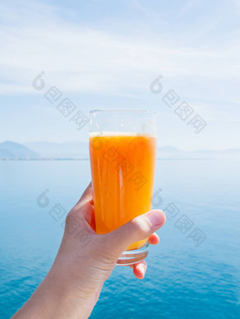 手新<strong>鲜</strong>的美味的<strong>鲜榨汁</strong>成熟的橙子玻璃平静海山地平线带火鸡