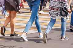 年轻的女人脚穿越城市街