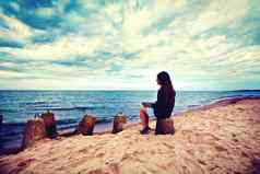 伤心孤独的女人坐着海滩