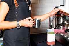手咖啡师不锈钢钢金属杯子使拿铁咖啡背景咖啡机模糊